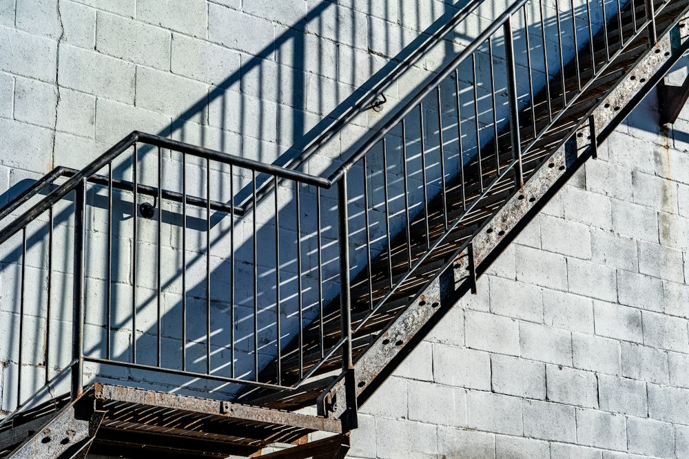 Escalera metálica exterior con baranda junto a un muro