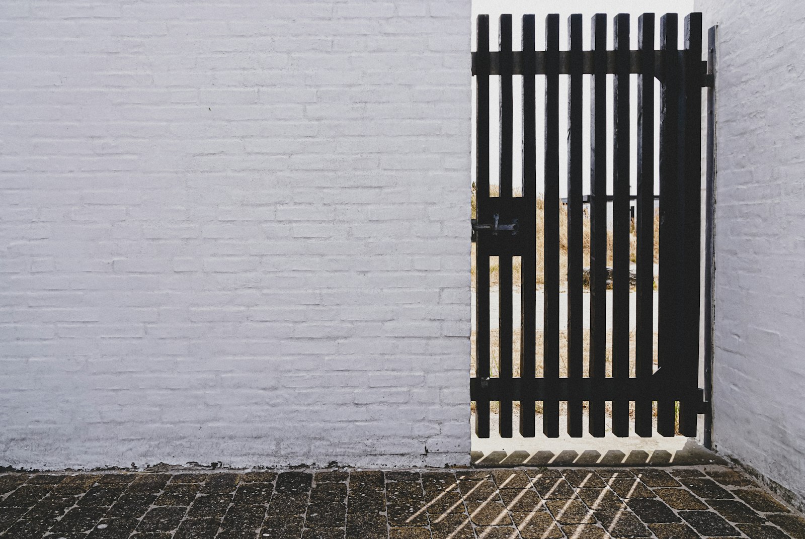 Puerta de reja de fierro negro de barrotes verticales en un muro blanco en Santiago